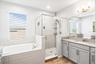 Primary bathroom with his and hers sinks, spa tub, walk in shower