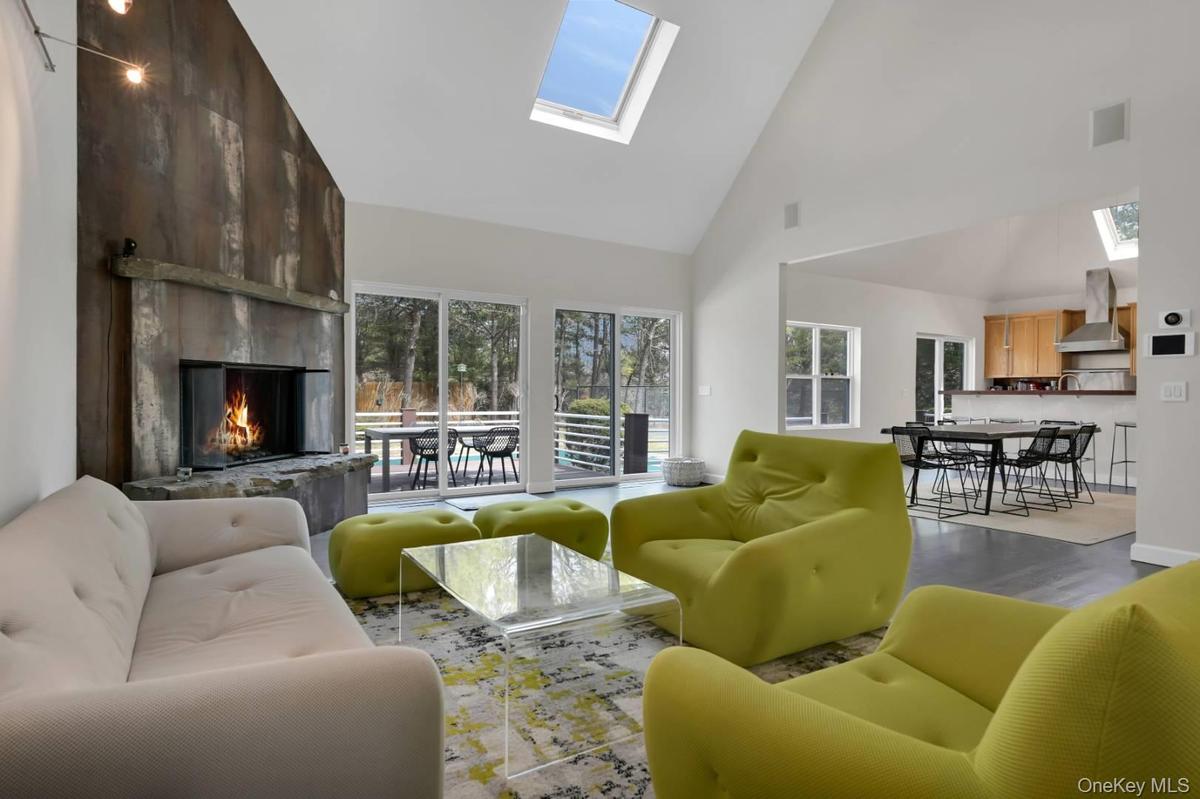 Living area featuring a skylight, visible vents, a premium fireplace, wood finished floors, and high vaulted ceiling
