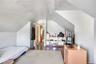 Spacious room featuring sloped ceilings, light-toned wall finishes, wood-finish flooring, and a doorway leading to an additional area