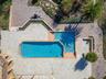 Outdoor amenities create a resort-style setting with a stunning pool featuring a waterfall edge, tennis courts, and a covered private boat dock. Addit