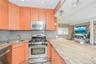 Kitchen featuring appliances with stainless steel finishes, open shelves, light stone counters, a peninsula, and recessed lighting