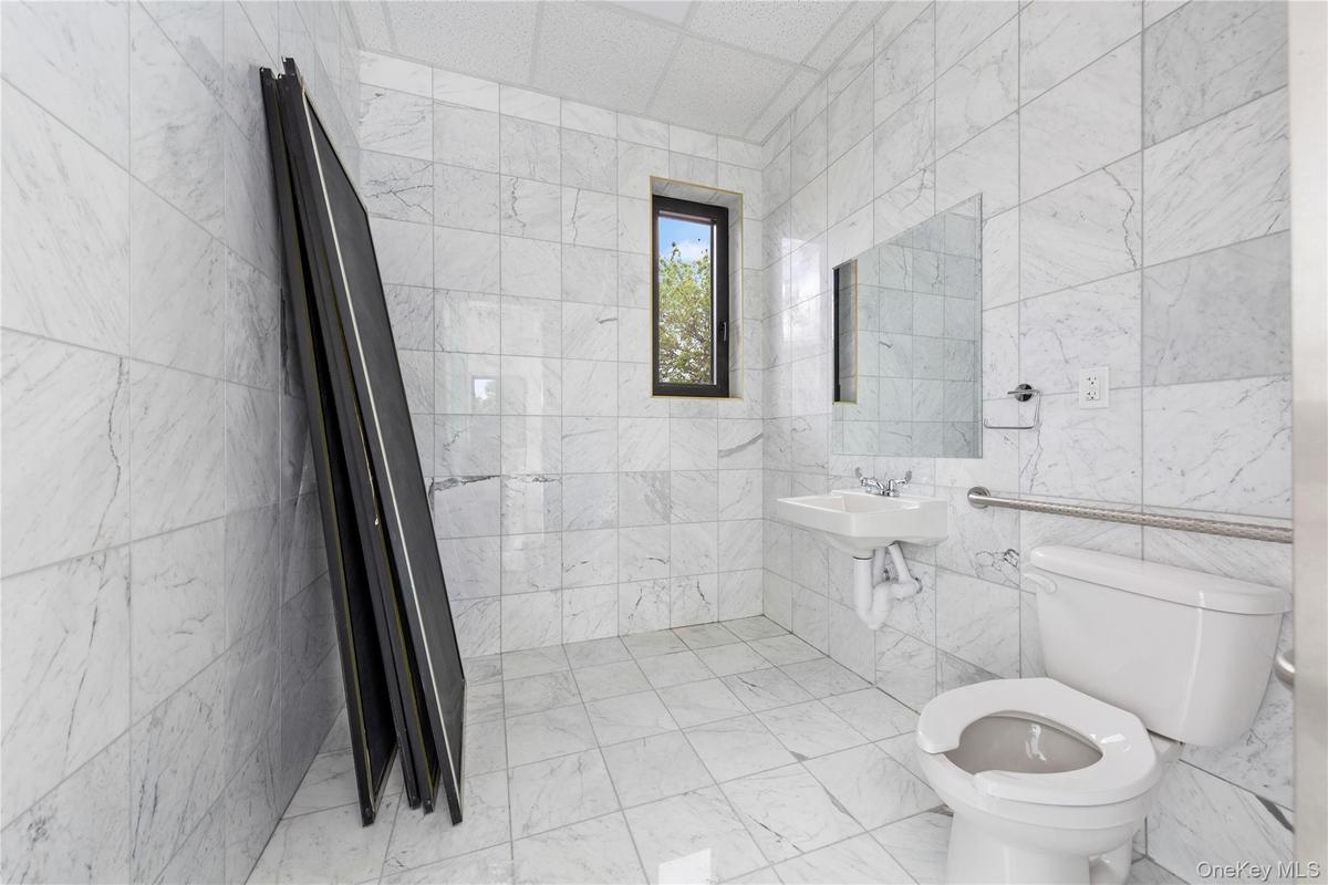 Bathroom featuring toilet, tile walls, and a sink