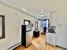 2 - Kitchen with a baseboard radiator, dark countertops, a sink, light wood-type flooring, and freestanding refrigerator