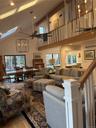 Living area with a chandelier, light wood finished floors, a skylight, ceiling fan, and vaulted ceiling