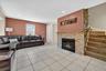 Living room with light tile patterned floors, a glass covered fireplace, recessed lighting, and stairs