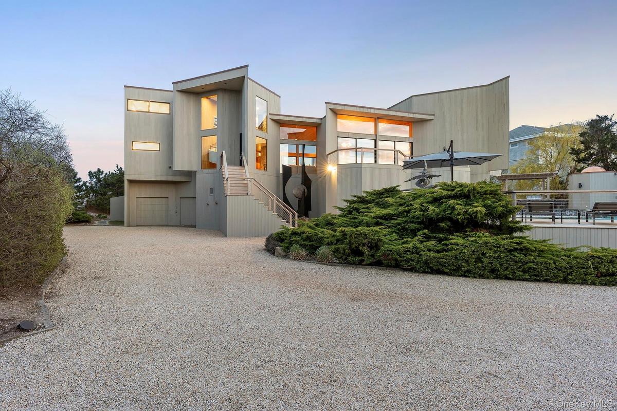 Modern home with stairway and gravel driveway