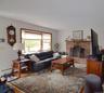 Living area featuring a brick fireplace with a wood mantel, a bay window with wood trim, and wood-finish flooring