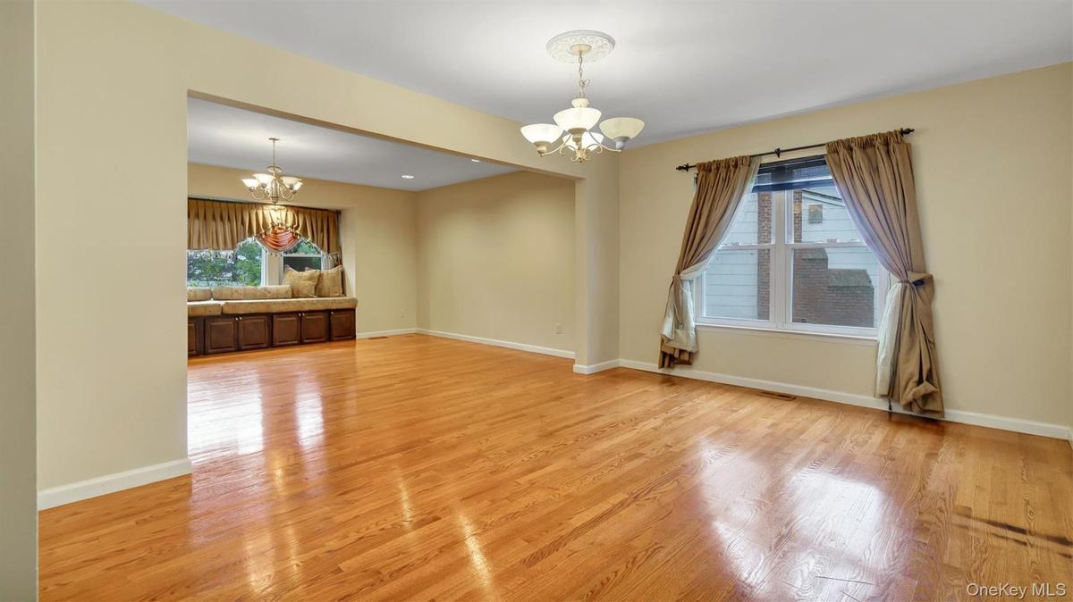 Spare room with a chandelier, light wood-style flooring, a wealth of natural light, and baseboards