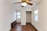 Recessed closet opening, wood-finish flooring, two windows with blinds, and ceiling fan with integrated lighting