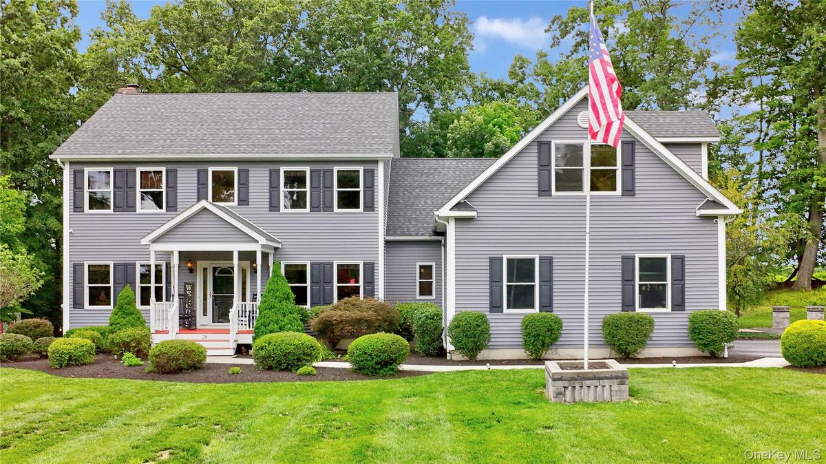 Two-story residence with legal accessory apartment featuring light gray siding, dark shutters, and a covered front porch with white railings