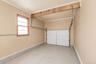 Garage interior featuring a single window with wood framing, beige painted walls, crown molding, and a sectional overhead door