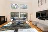 Living room featuring a high ceiling, a glass covered fireplace, and light wood-style flooring