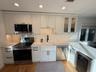 Kitchen with white cabinets, appliances with stainless steel finishes, beverage cooler, and sink