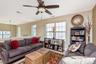 Living area featuring a ceiling fan with integrated lighting, multiple windows with blinds, and a partial wall separating spaces