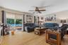 Spacious interior featuring wood-finish flooring, a ceiling fan, and sliding glass doors opening to an outdoor area with a visible pool