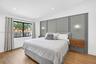 Primary bedroom w/ attached nightstands, feature wall and reading sconces - overlooks front of property