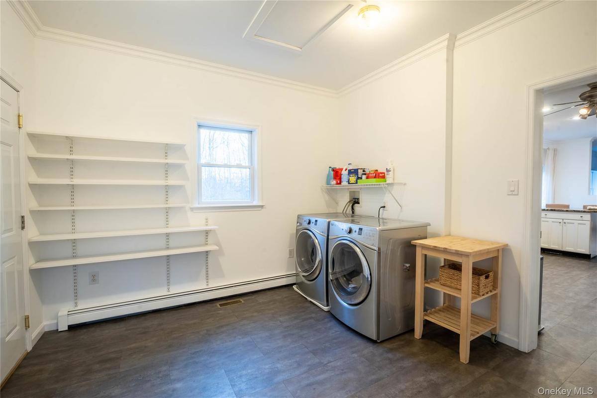 Washroom with laundry area, crown molding, baseboard heating, and washer and dryer