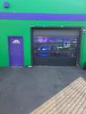Commercial building exterior featuring a vibrant green facade with a purple accent band