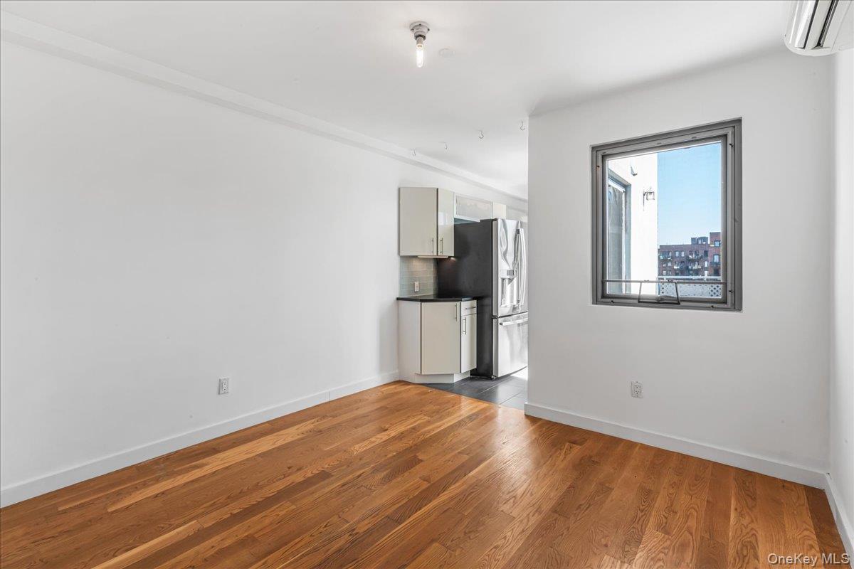 Unfurnished living room featuring a wall mounted air conditioner and wood finished floors
