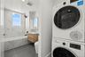Laundry area with stacked washer / drying machine, recessed lighting, and dark tile patterned flooring