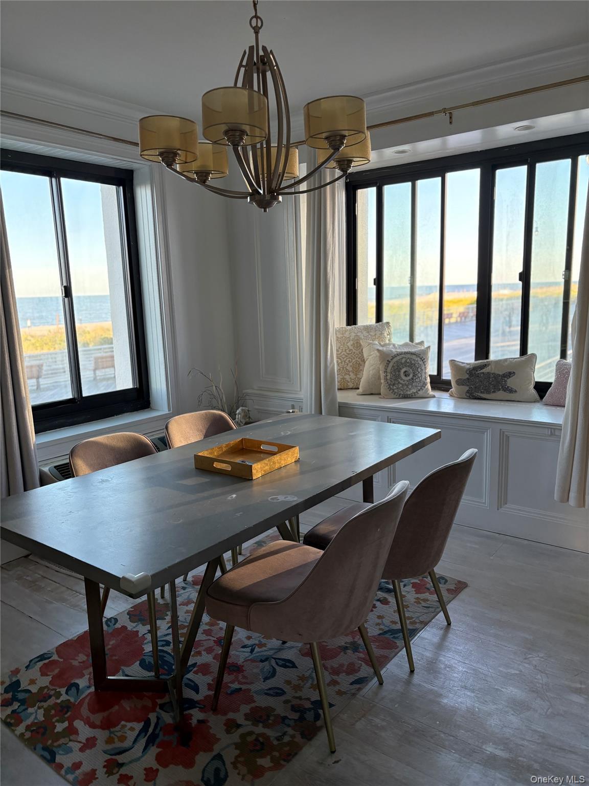 Dining area with a chandelier, crown molding, light wood-style flooring, and a water view