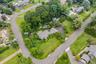 Aerial view of property and surrounding area featuring a pool area and nearby suburban area