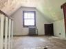 Attic- front room  space featuring an operable window with wood trim, a vintage-style radiator, and a built-in storage door