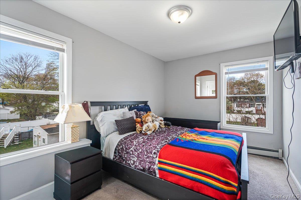 Bright bedroom featuring two windows with white trim, light gray walls, and carpeting. Can House a Queen Size Bedroom Set. Deep Closet