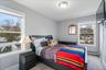 Bright bedroom featuring two windows with white trim, light gray walls, and carpeting. Can House a Queen Size Bedroom Set. Deep Closet