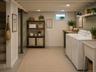 Unfinished basement featuring concrete flooring, exposed ceiling joists, washer and dryer, and a utility area with water heater and furnaceDigitally s