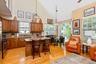 Open-concept Kitchen featuring vaulted ceilings, wood-finish flooring, a large island with seating, stainless steel appliances, and a glass sliding do