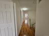 Hallway featuring baseboards, an upstairs landing, and wood finished floors