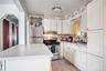 Bright kitchen featuring white cabinetry, a white countertop island, stainless steel appliances, and a marble-patterned tile backsplash