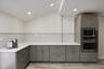 Modern kitchen featuring gray cabinetry, white subway tile backsplash, white countertops, stainless steel built-in appliances, and recessed lighting