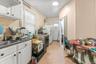 Kitchen with light tile patterned floors, tasteful backsplash, dark countertops, white cabinets, and white appliances