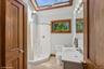 Bathroom with a skylight, vanity, light tile patterned floors, and a shower stall