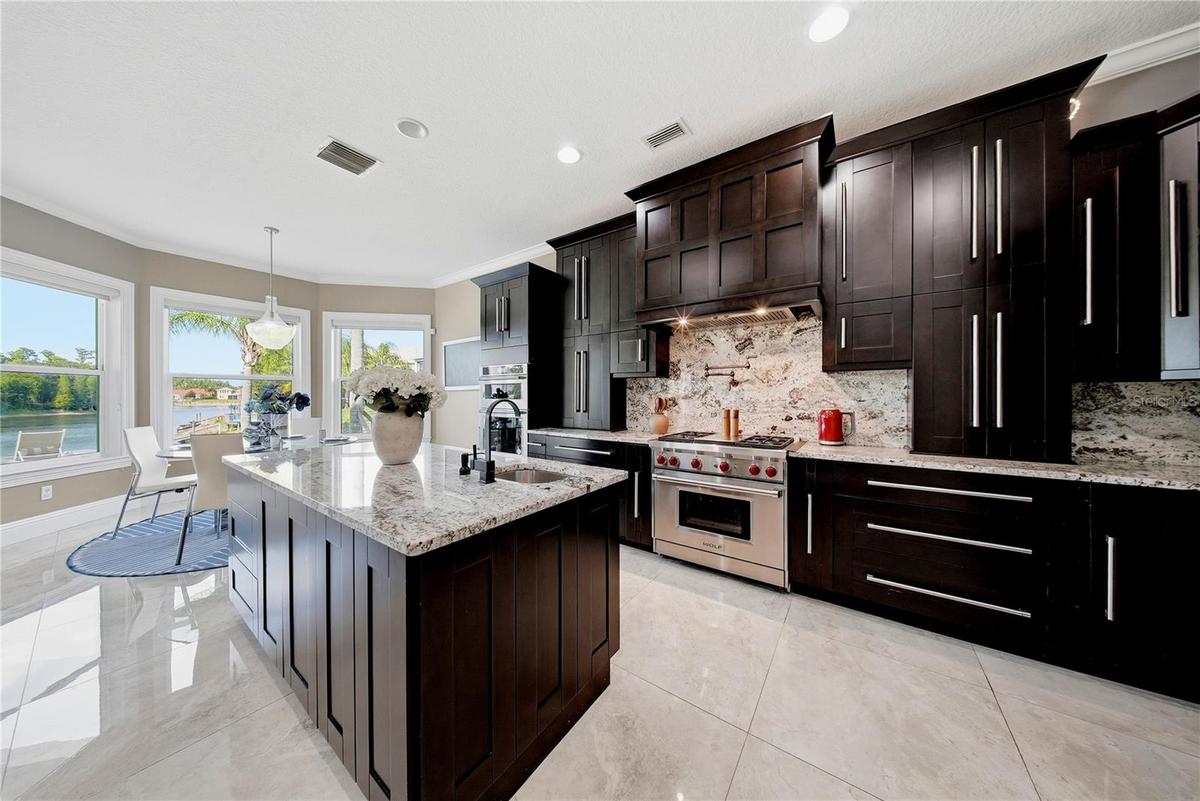 Chef's kitchen with granite counters that continue onto the backsplash