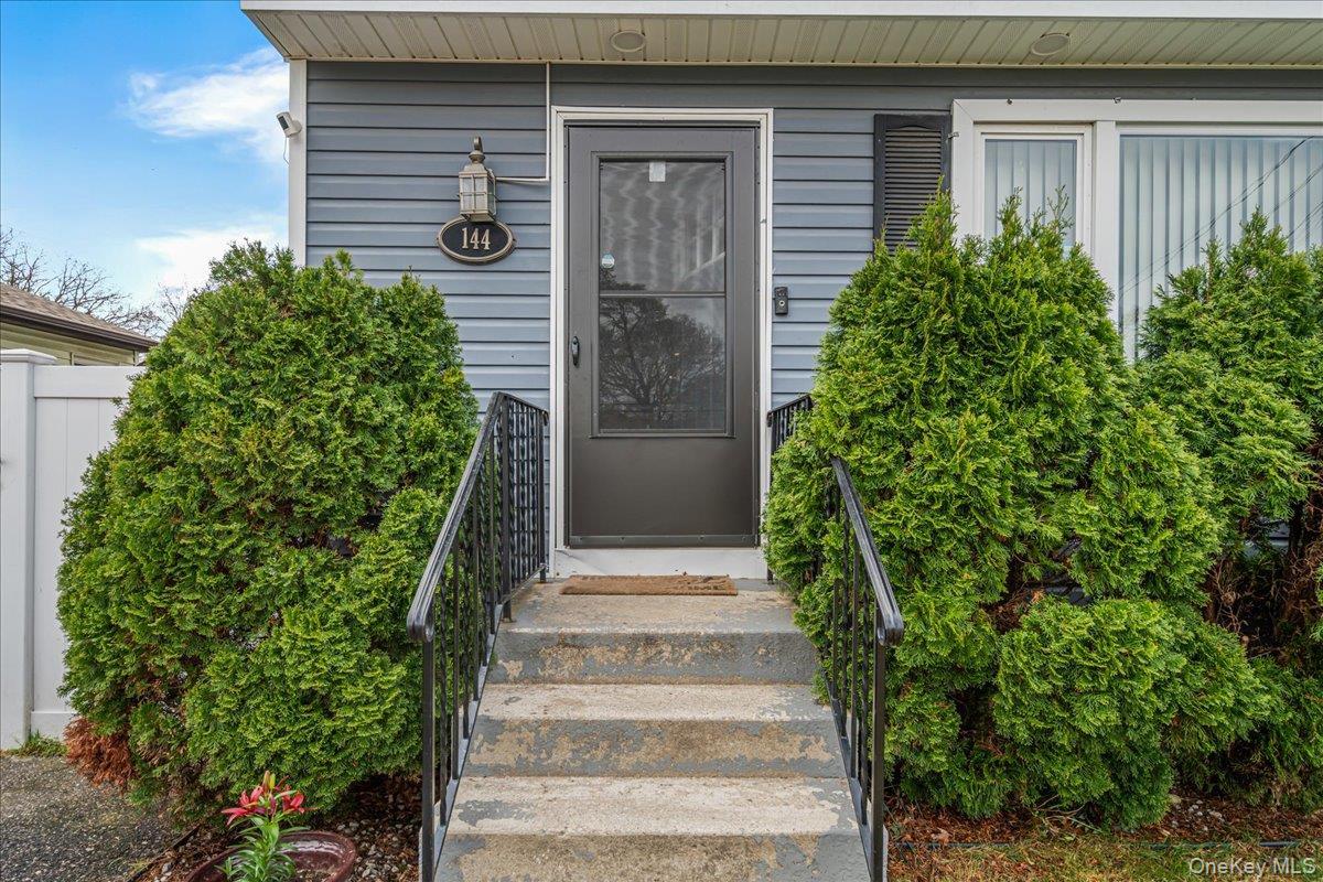 Front entry featuring a dark-paneled door with an integrated screen, concrete steps, and black metal railings, In-Ground Sprinklers (  Front Only)