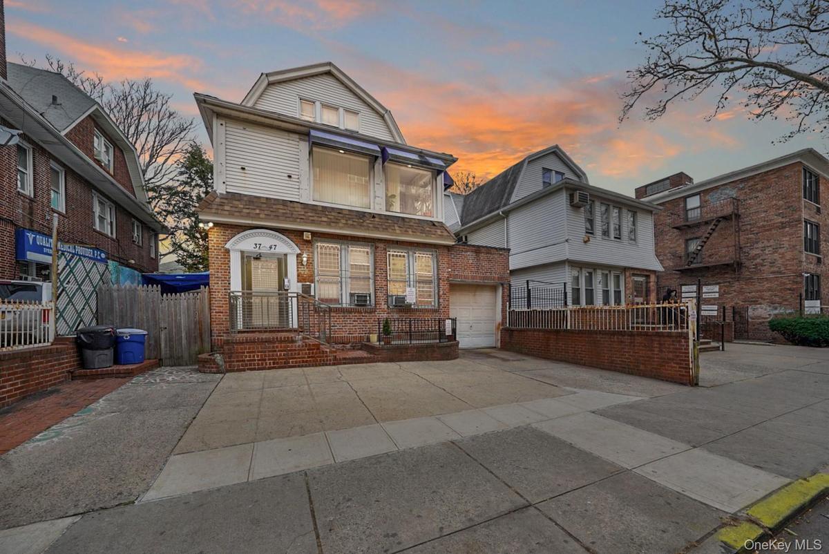 Front exterior elevation of 37-47 76th Street, Jackson Heights, NY 11372, featuring a three-family residence with a private driveway, attached garage,