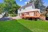 Back of house with a lawn, a chimney, a shingled roof, and a wooden deck
