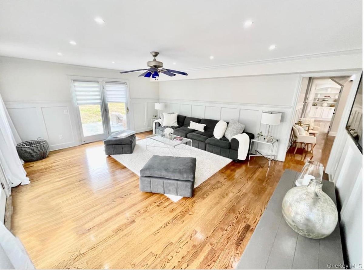 Living area featuring a decorative wall, wood finished floors, wainscoting, recessed lighting, and a ceiling fan