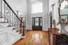 Two-story entryway with a decorative arched window, dark wood-finish flooring, and a staircase featuring intricate wrought iron balusters