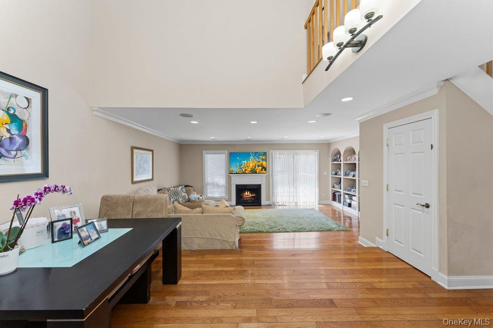 Open-concept living space featuring wood-finish flooring, a fireplace, arched built-in shelving, a sliding glass door, and recessed lighting