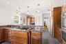Designed for both function and gathering, the kitchen features rich cherry cabinetry, expansive granite countertops, island seating, stainless steel a