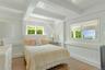 Bedroom with wood finished floors, multiple windows, beam ceiling, and a decorative wall