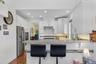 Kitchen with white cabinets, a peninsula, dark wood-style flooring, appliances with stainless steel finishes, and a kitchen breakfast bar
