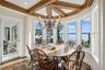 Dining space with a water view, beamed ceiling, dark wood finished floors, coffered ceiling, and a chandelier