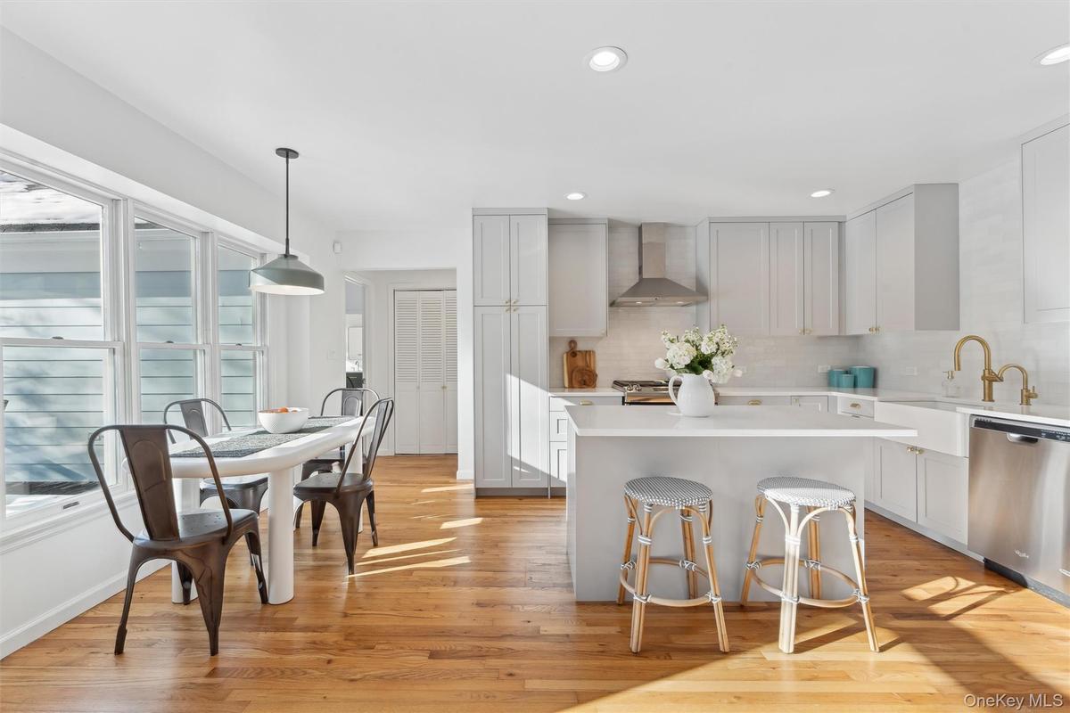 Kitchen with light countertops, a kitchen island,  dishwasher, and light wood floors