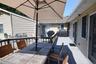 Spacious outdoor deck featuring gray wood-finish flooring, dark wood railings, and direct access to the interior via sliding glass doors