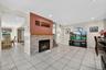 Living room featuring light tile patterned flooring, a glass covered fireplace, recessed lighting, and a baseboard heating unit